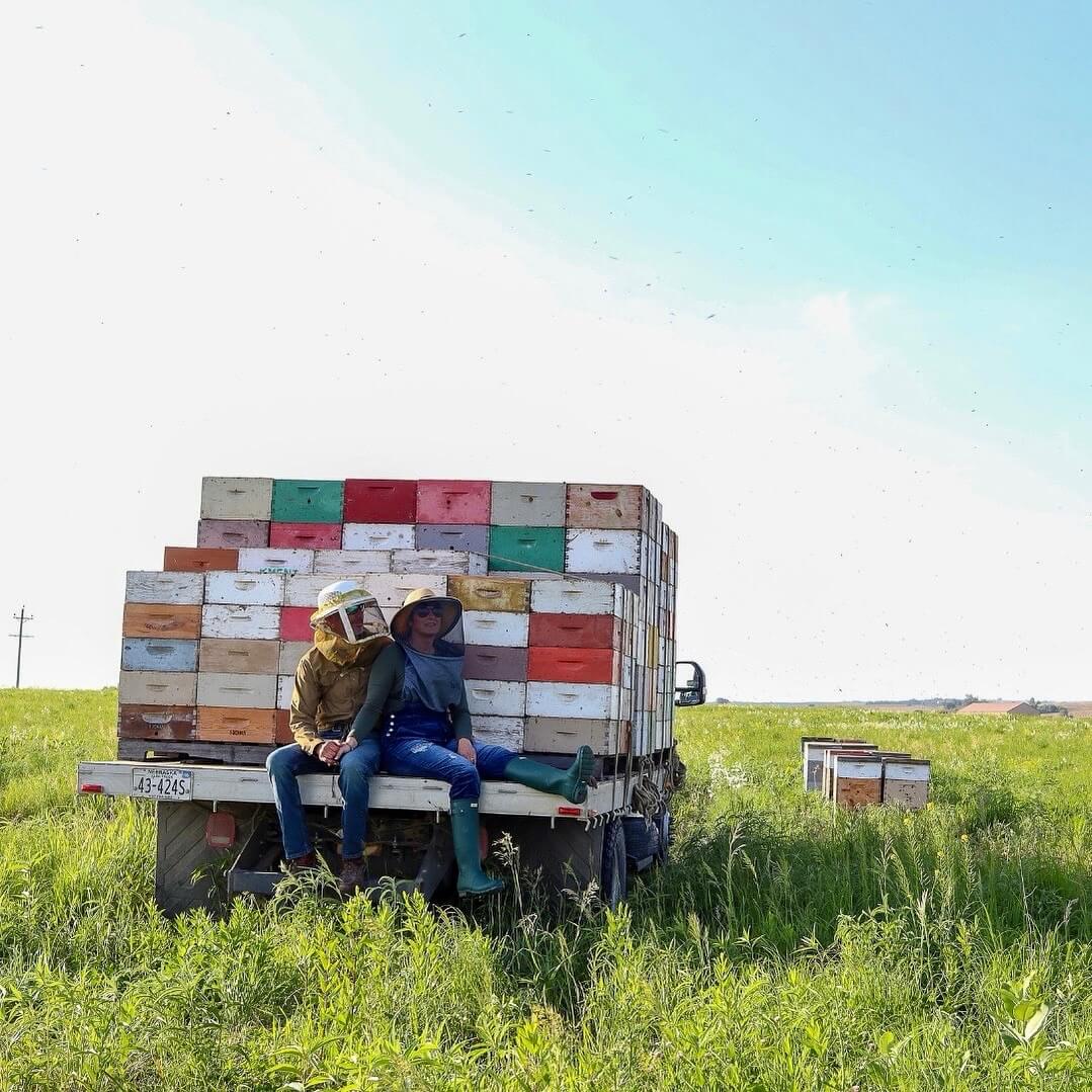 Fat Head Honey Farm owners sitting on the back of a truck filled with bee hives
